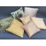 Two floral needlework cushions together with five silk cushions in pale apricot and pink