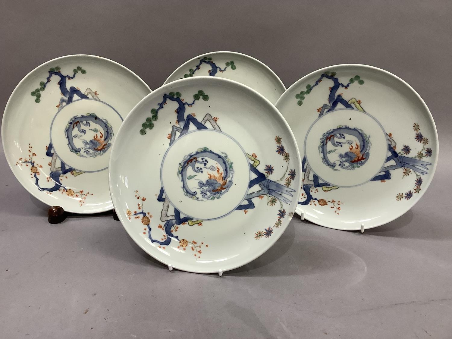 A set of four Japanese porcelain plates, each decorated to the centre with a stylised dragon, the