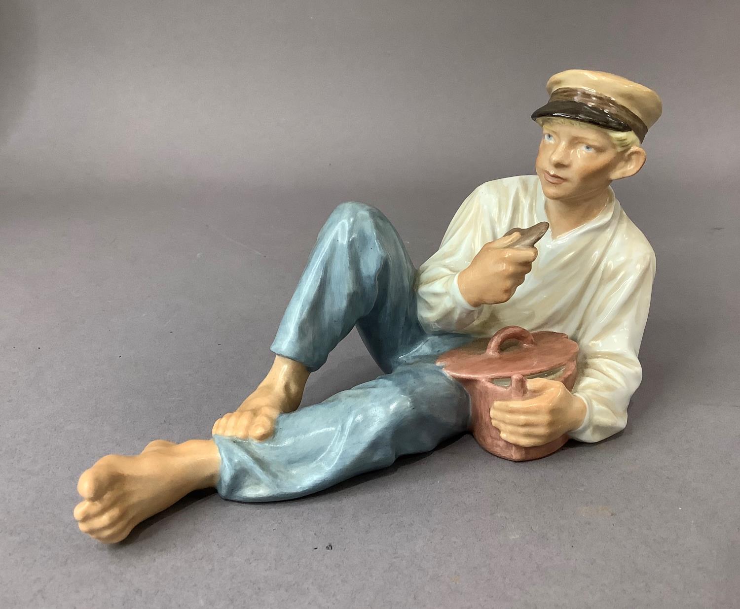 A Royal Copenhagen figure of a country boy resting as he eats his lunch, printed and underglaze blue