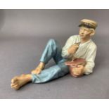 A Royal Copenhagen figure of a country boy resting as he eats his lunch, printed and underglaze blue