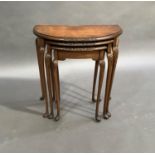 A set of three burr walnut veneered occasional tables of D-shape, foliate carved rims, on shell