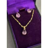 An amethyst pendant and ear stud suite in yellow metal (tests as 18ct gold) each claw set with a