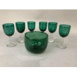 A set of six emerald green glass wines and an emerald green glass finger bowl, the latter 9cm high