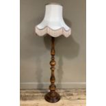A stained beech, knopped and baluster stemmed standard lamp on circular base with fringed cream