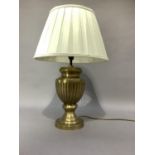 A brass table lamp of fluted urn form on circular base and with pleated cream shade, 55cm high