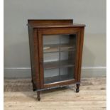 An oak dwarf display cabinet with upstand, applied beaded moulding, the lead glazed door revealing