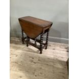 An oak gate leg table, the oval top on barley turned legs joined by stretchers, 75cm wide