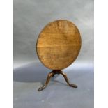 A George III oak tripod table, circular top above a baluster turned column, three outswept legs with