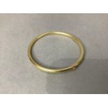 A stiff hinged bangle, circular, hallow section in yellow metal (tests as 18ct gold)