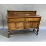 An oak sideboard with upstand, rectangular top above two short drawers and four panelled