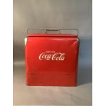 A Vintage Coca Cola cool box with hinged carrying handle, the front embossed and highlighted in
