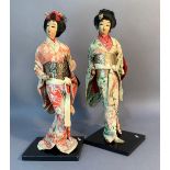 A pair of Japanese costume dolls, each on ebonised plinth