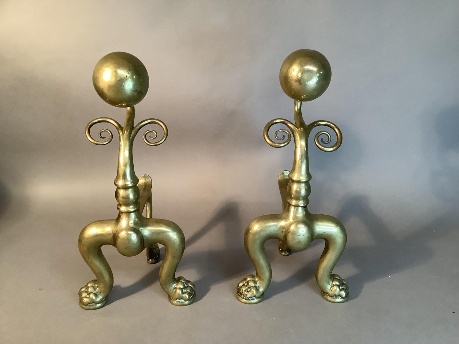 A pair of Victorian brass andirons with sphere and scroll uprights on pair of bold cabriole legs