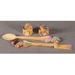 A pair of vintage salad servers and napkin rings each carved with a character head and shoulders,