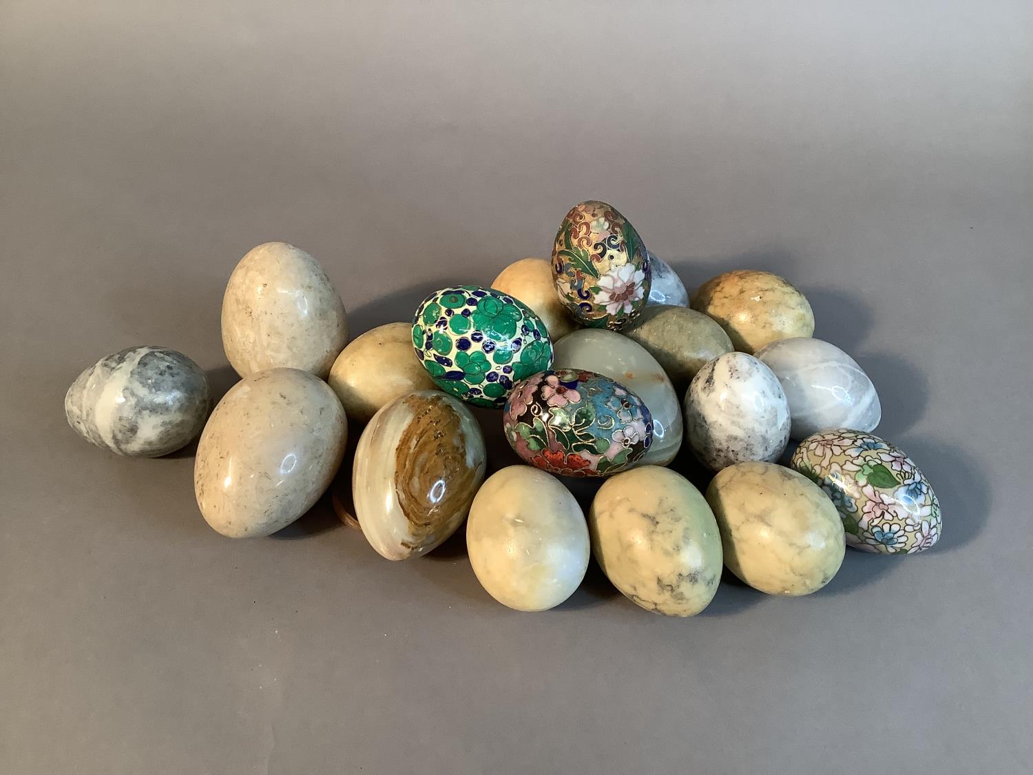 A small collection of alabaster, marble, onyx, enamelled and papier maché eggs