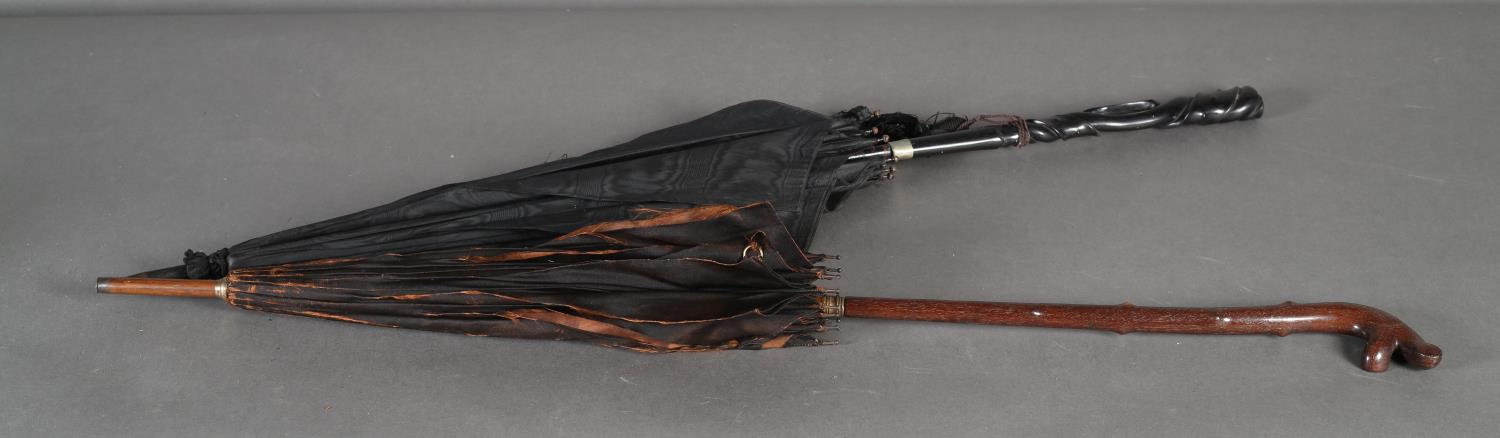 A Paragon & Sons black silk parasol with tapered pierced ebony handle ribbon carved, white metal