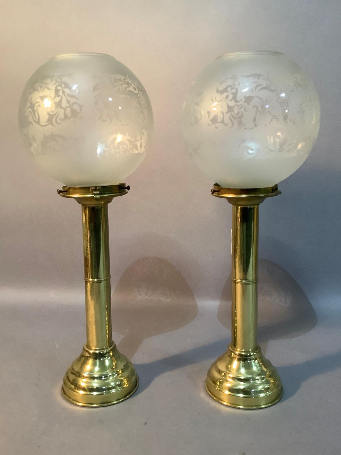 A pair of gilt metal candle holders with opaque glass globes