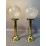 A pair of gilt metal candle holders with opaque glass globes