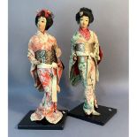 A pair of Japanese costume dolls, each on ebonised plinth