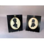 A pair of pen and ink silhouettes of a lady and gentleman in ebonized frame with gilt metal acorn