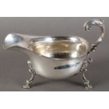 A GEORGE III STYLE SILVER SAUCE BOAT with acanthus capped flying scroll handle, shaped rim and three