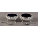 A PAIR OF VICTORIAN SILVER COMPRESSED CIRCULAR SALTS, the bodies embossed with flowers and leaves,