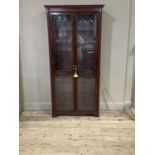 A reproduction mahogany display cabinet with flared cornice, shallow frieze, pair of glass doors cut