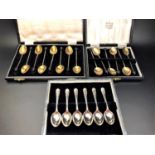 THREE CASED SETS OF SIX SILVER COFFEE SPOONS comprising two silver gilt sets with harlequin enamel