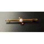 PRETTY OPAL AND SEED PEARL BAR BROOCH in nine carat gold, the central round cabochon opal with
