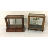 TWO SETS OF SCIENTIFIC SCALES both contained in glass and mahogany cabinets (2)