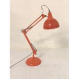 ORANGE ANGLE POISE LAMP raised on a circular base