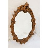 GILT PLASTER OVAL WALL MIRROR with an ornate frame decorated with flowerheads and leaves, 65cm high