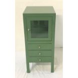 GREEN METAL CABINET the glazed door and side panels above three drawers, standing on plain supports,