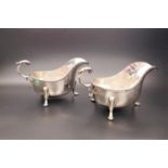 PAIR OF EDWARD VIII SILVER SAUCE BOATS both with shaped rims scroll handles and standing on three