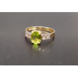 PERIDOT AND DIAMOND RING the central oval cut peridot approximately 1ct flanked by two diamonds to