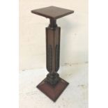 MAHOGANY TORCHERE with a square top above a carved oblong column decorated with leaf motifs,