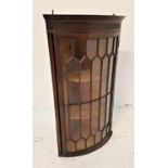 BOW FRONT MAHOGANY HANGING CORNER CABINET with an astragal glazed door opening to reveal shaped