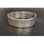 VICTORIAN STYLE SILVER BANGLE the hinged bangle with engraved scroll decoration and safety chain,