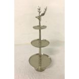 POLISHED STEEL GRADUATED THREE TIER CAKE STAND surmounted with a stag's head, 98cm high