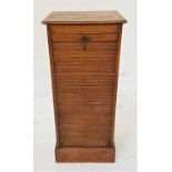 OAK TAMBOUR FRONT MUSIC CABINET with a drop down door revealing nine drawers, standing on a plinth