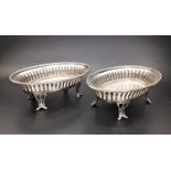 PAIR OF GEORGE V PIERCED SILVER BON-BON DISHES standing on pierced scroll decorated feet,