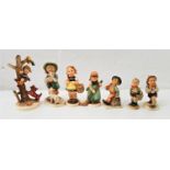 SEVEN GOEBEL HUMMEL FIGURES including a boy climbing an apple tree with dog at base, a girl