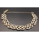ATTRACTIVE NINE CARAT GOLD CELTIC KNOT DESIGN BRACELET with seven entwined links and safety chain,