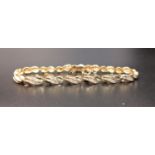 DIAMOND SET FOURTEEN CARAT GOLD BRACELET each of the sixteen links of crossover design and set