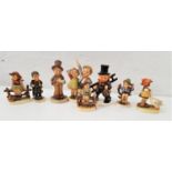 EIGHT GOEBEL HUMMEL FIGURES including a boy and a girl sitting on fences, a boy in top hat singing