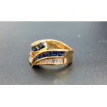 ATTRACTIVE DIAMOND AND SAPPHIRE CROSSOVER RING with channel set baguette cut diamonds and cabochon