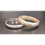 TWO SILVER HINGED BANGLES both with engraved scroll decoration and safety chains, the larger with