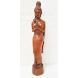 CARVED TEAK BALINESE FIGURE of a lady in traditional dress with hands in prayer pose, raised on