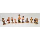 NINE GOEBEL HUMMEL FIGURES including a boy sitting on a fence, a girl with watering can, a boy