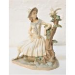 NAO PORCELAIN FIGURINE of a young girl seated by a tree looking at a dove, 24cm high
